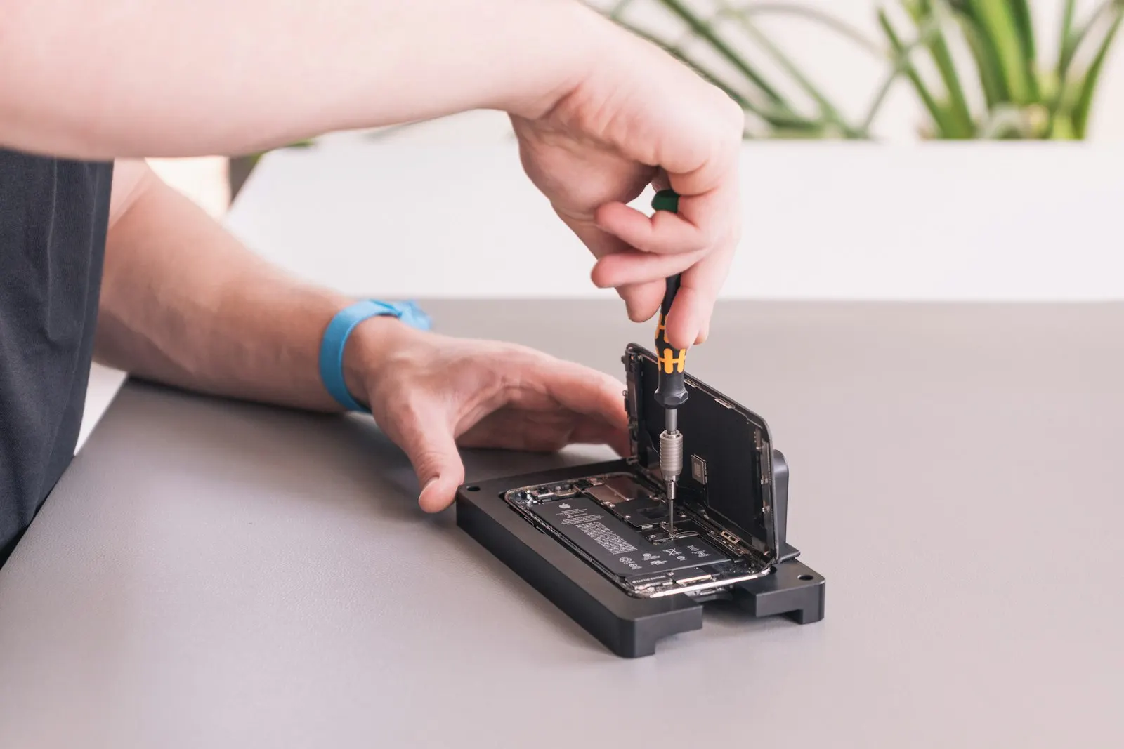 Réparateur qui dévisse un smartphone ouvert, posé sur un support de réparation
