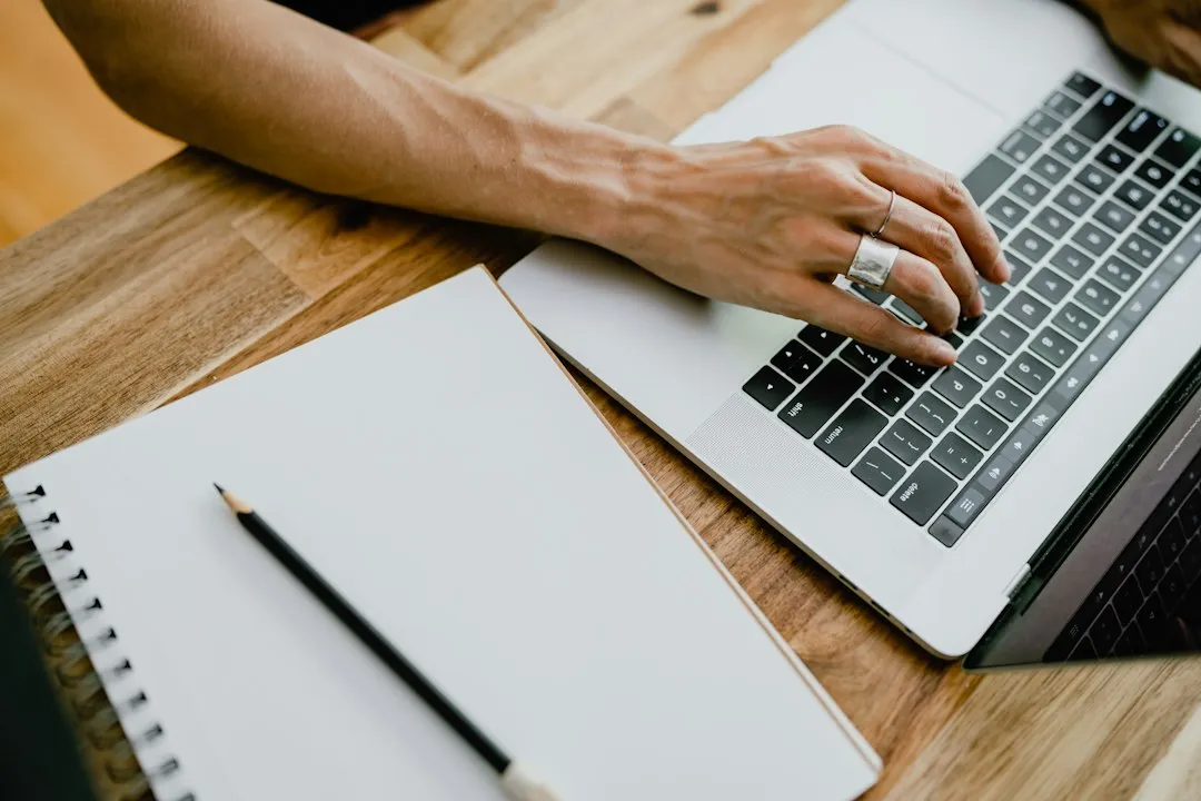 Mains posées sur le clavier d'un ordinateur portable, en train de remplir un formulaire en ligne