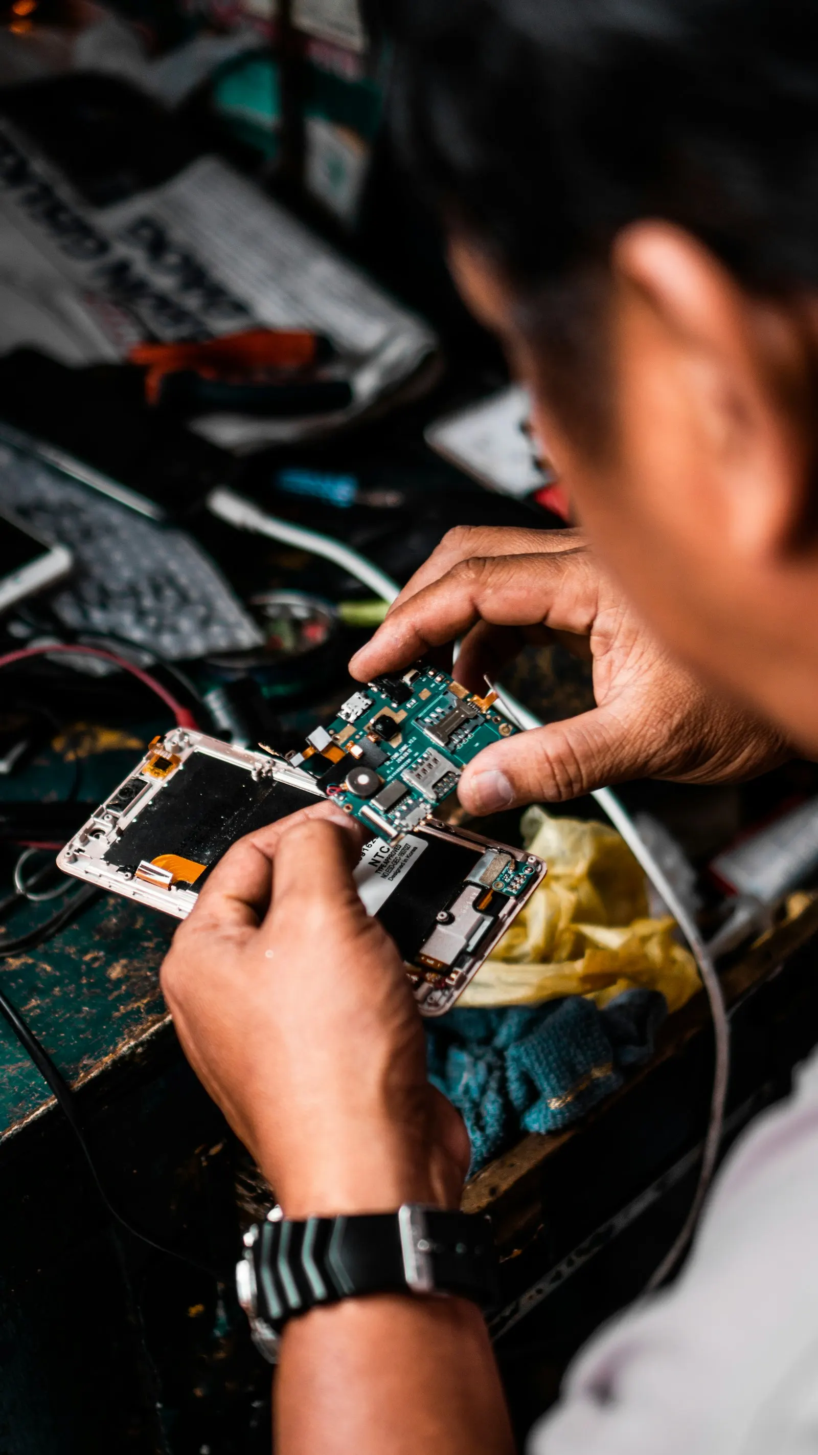 Mains d'un technicien qui réparent la carte électronique d'un smartphone