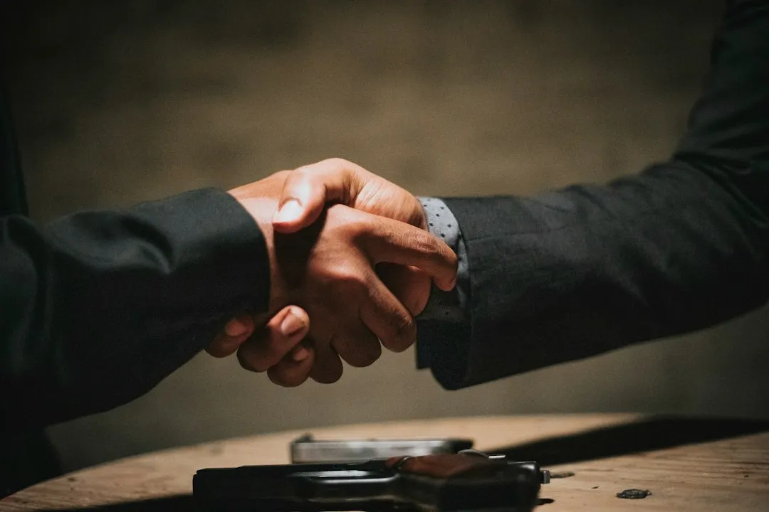 Deux personnes qui se serrent la main au-dessus d'une table en bois, comme à la conclusion d'une vente