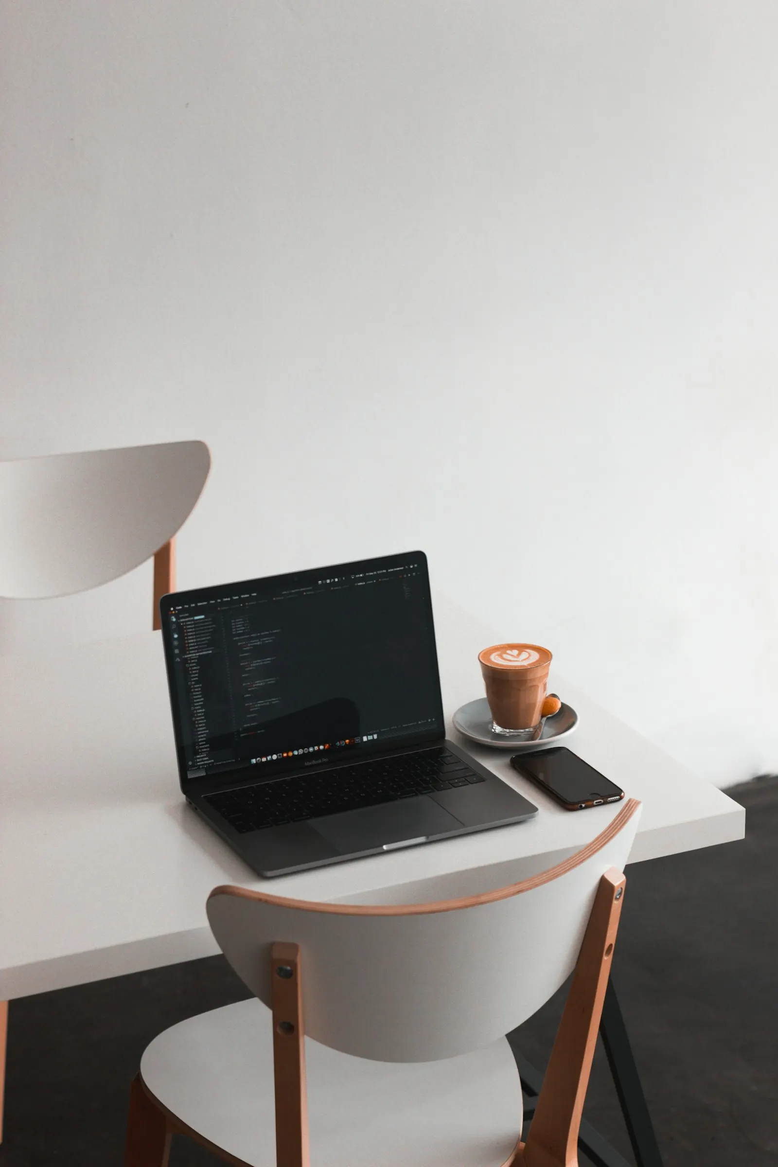 Ordinateur portable ouvert sur un bureau blanc à côté d'un café et d'un smartphone