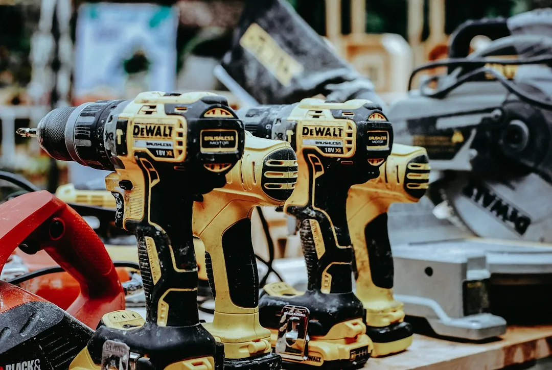 Deux perceuses-visseuses sans fil jaunes et noires avec leurs batteries, posées sur une table