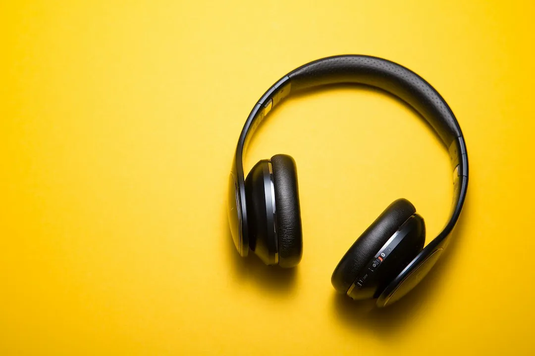 Casque sans fil noir posé à plat sur un fond jaune uni, vu de dessus