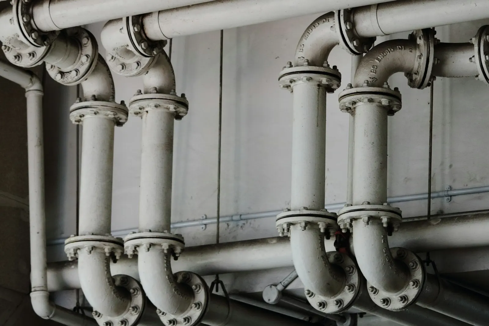 Tuyaux de chauffage gris le long d'un mur, en noir et blanc