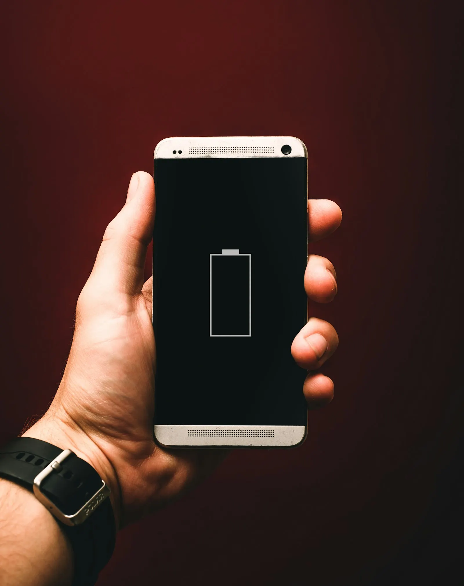 Main qui tient un smartphone affichant une batterie vide