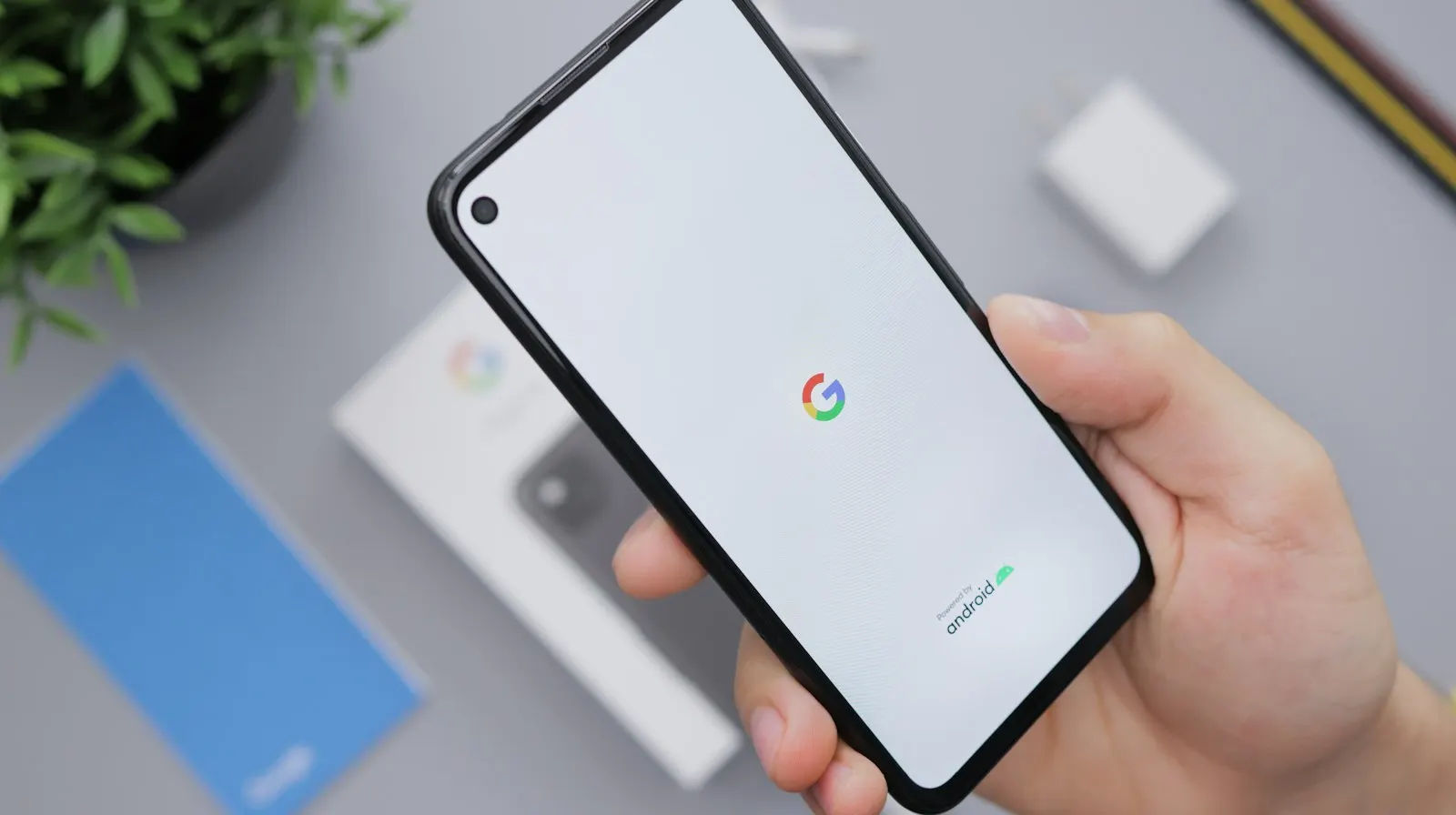 Main qui tient un Google Pixel en train de démarrer, logo Google à l'écran