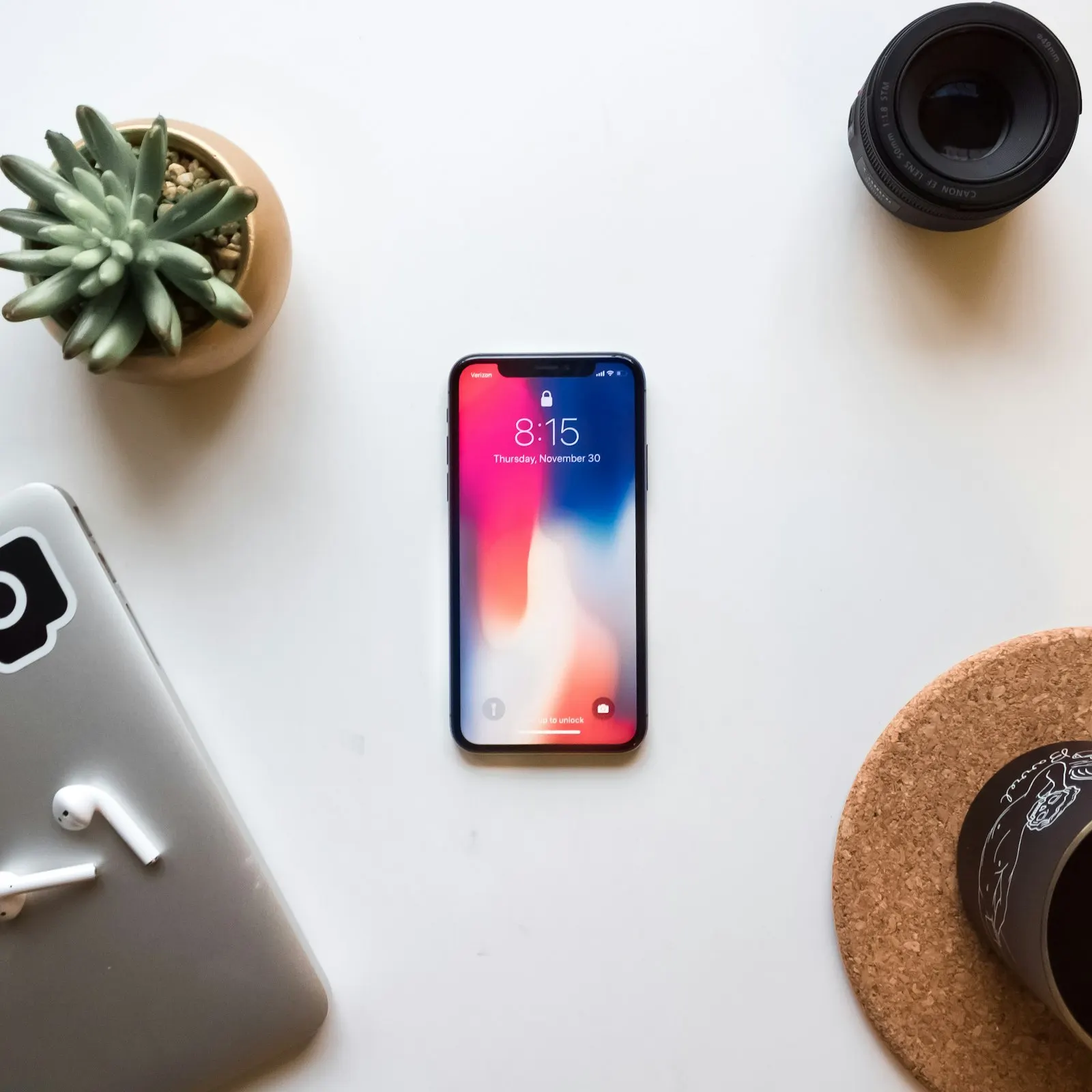 iPhone allumé posé sur une table blanche à côté d'une plante grasse
