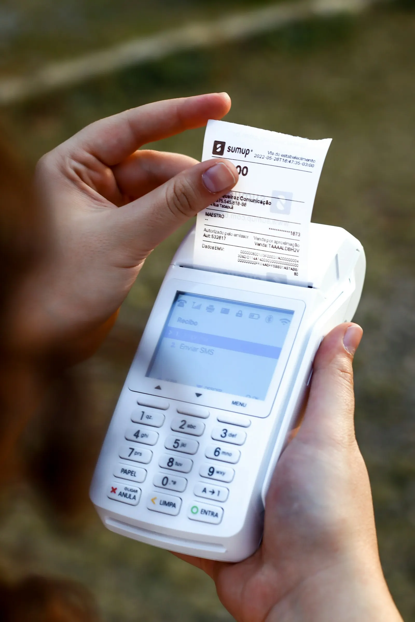 Main qui tient un terminal de paiement en train d'imprimer le ticket de caisse