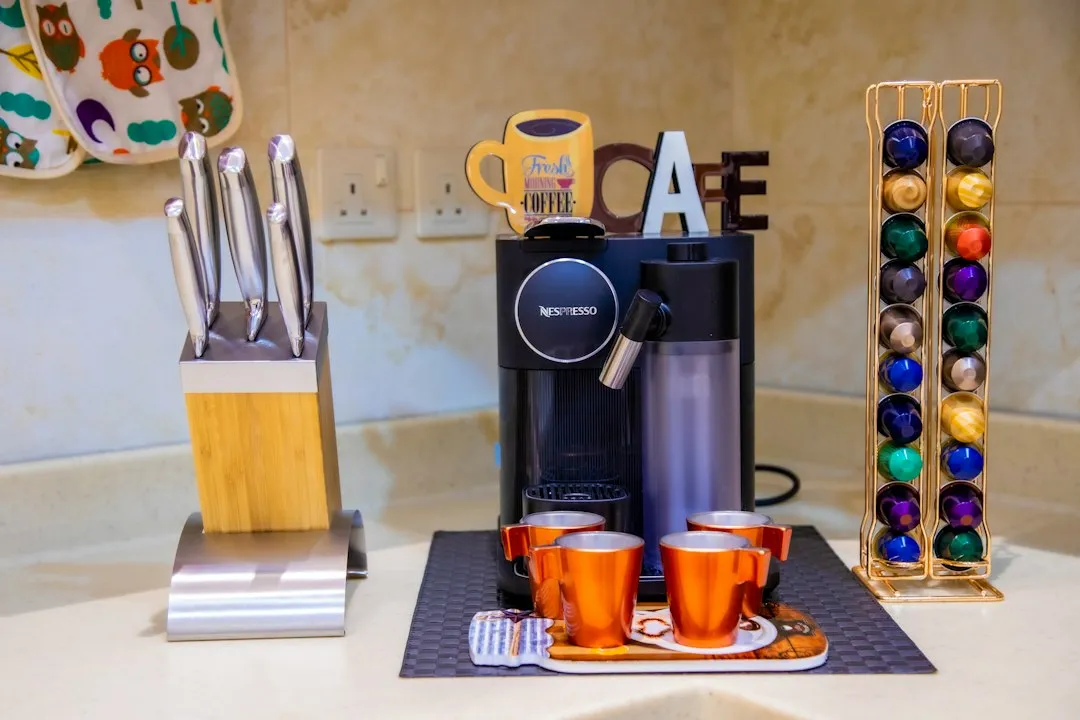 Machine à café Nespresso noire et argentée avec mousseur à lait, posée sur un plan de travail de cuisine