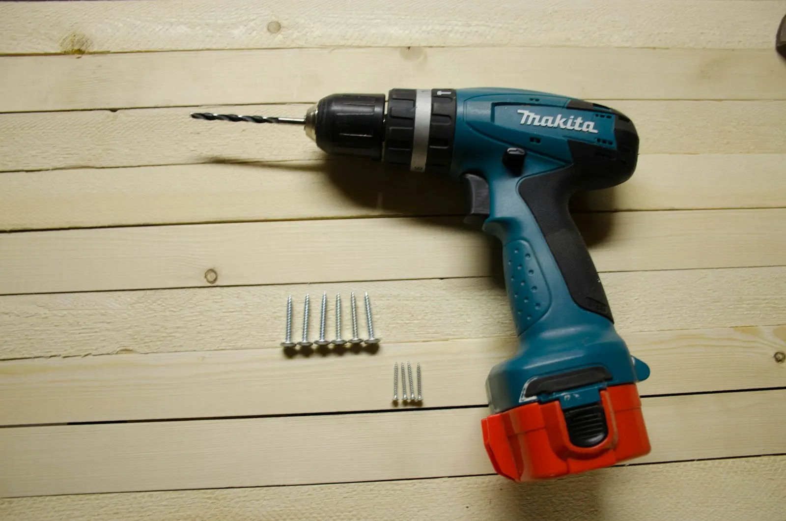 Perceuse-visseuse sans fil Makita posée sur des planches avec quelques vis