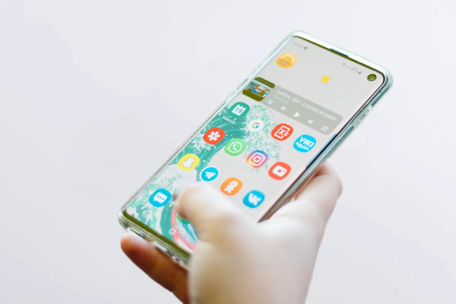 Main qui tient un smartphone Samsung Galaxy, écran d'accueil affiché