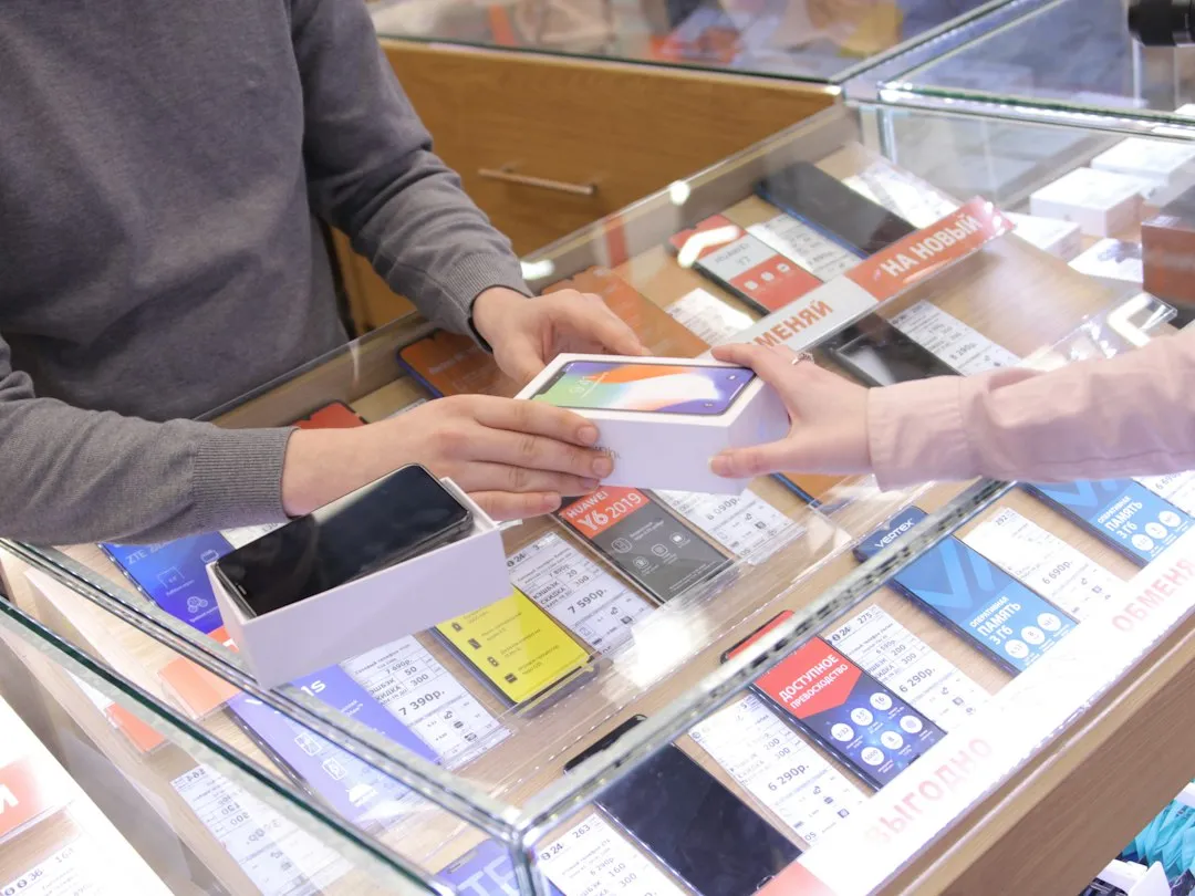 Client qui remet son smartphone à un conseiller au comptoir d'une boutique de téléphonie
