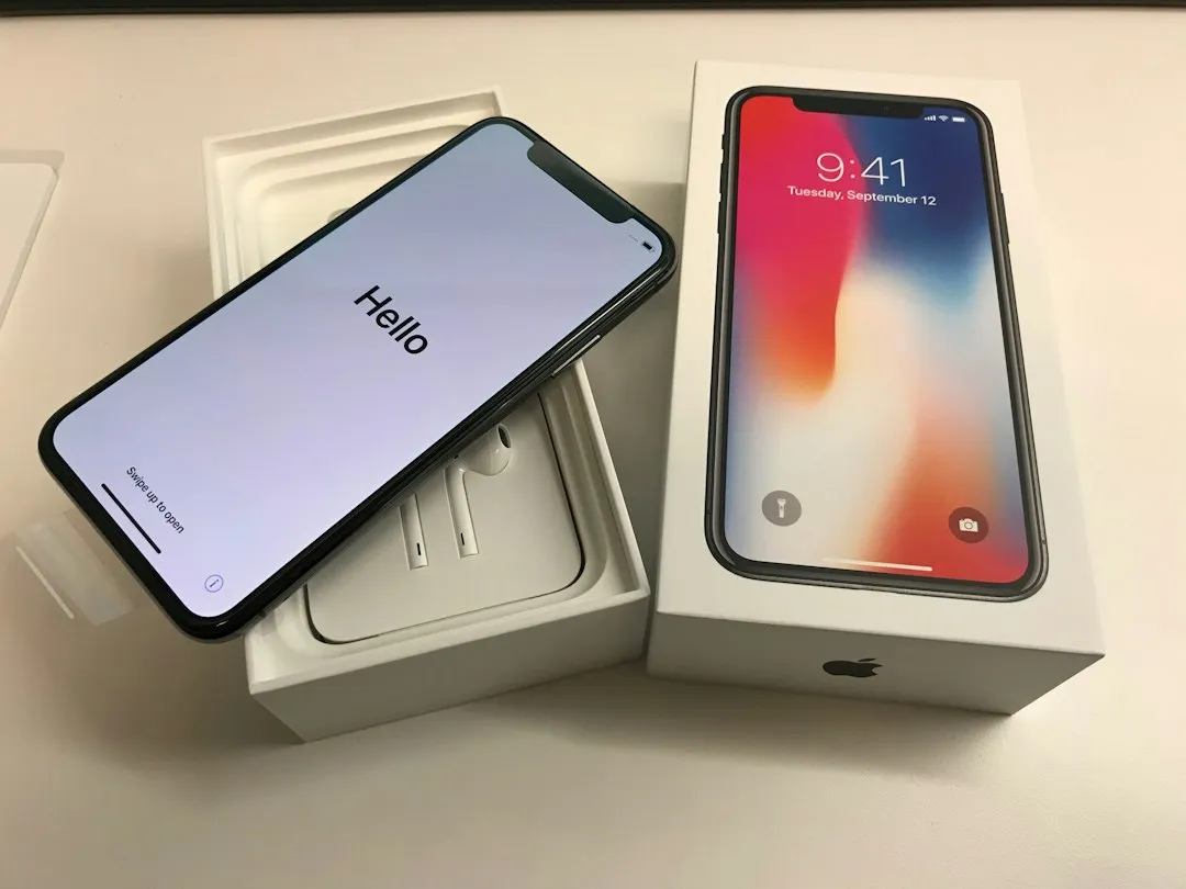 Smartphone neuf qui affiche « Hello » à l'écran, posé à côté de sa boîte blanche d'origine