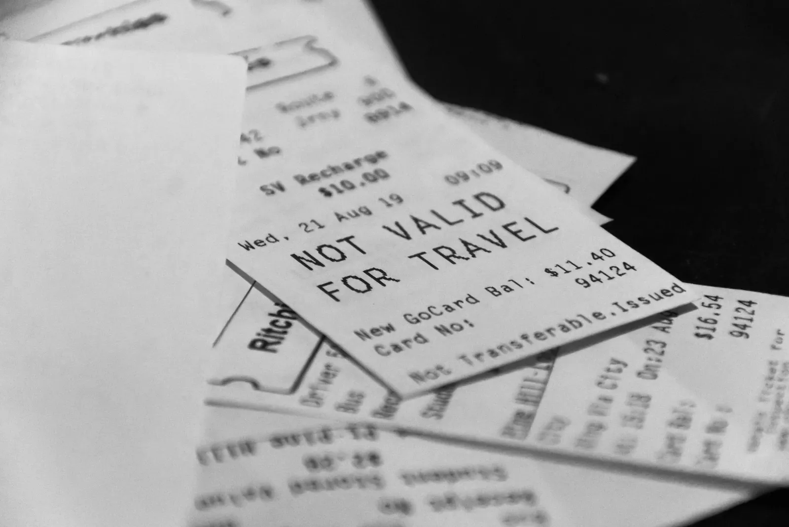 Plusieurs tickets de transport imprimés, empilés en vrac sur une table sombre, photo en noir et blanc