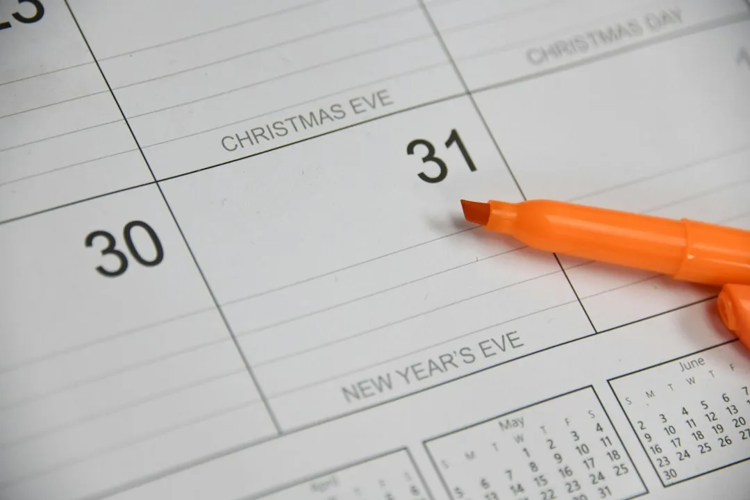 Feutre noir posé sur un calendrier papier mensuel, cases blanches vues de près