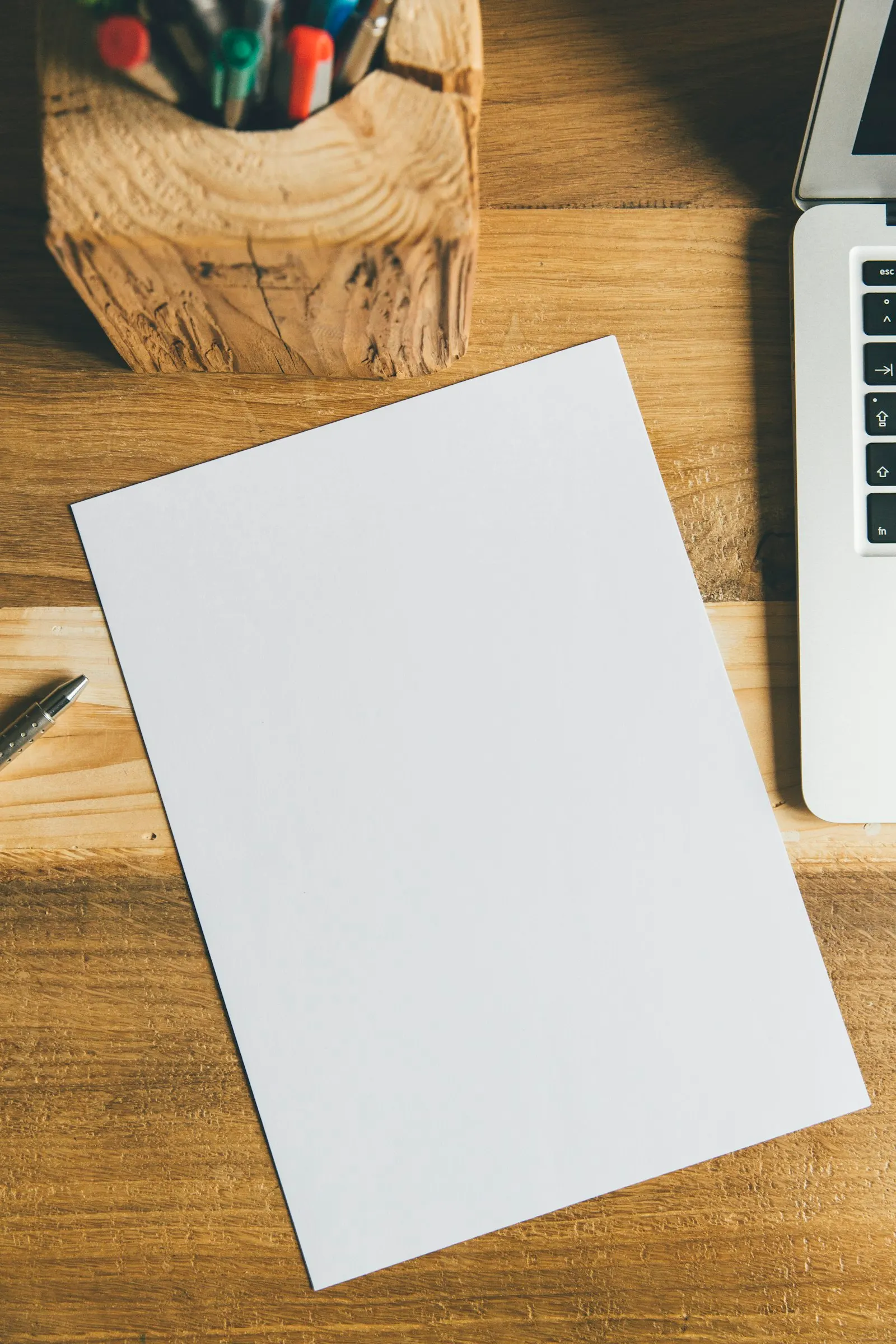 Feuille blanche et stylo posés sur un bureau en bois, prêts pour écrire une réclamation
