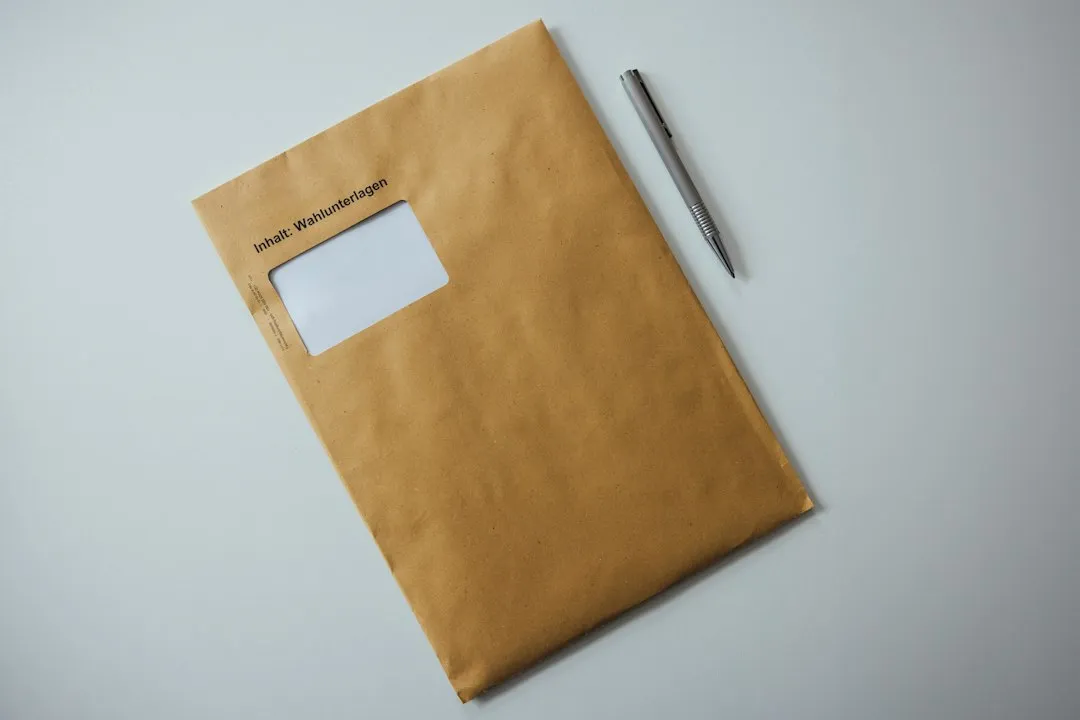 Enveloppe en papier kraft posée sur une table claire, un stylo noir déposé dessus